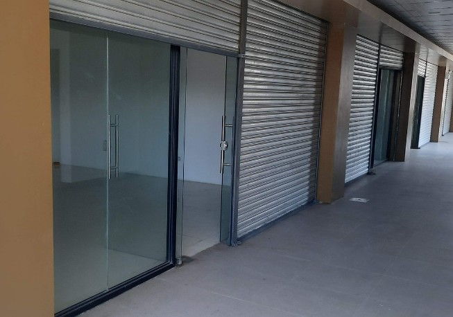 Cierres enrollables metálicos bajados junto a escaparates de vidrio en una galería comercial de Burgos