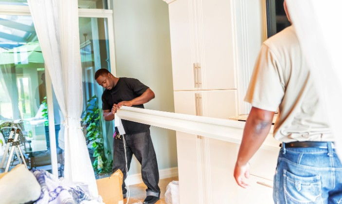 Dos operarios entrando el cajón compacto de una persiana nueva en una vivienda para su instalación en Burgos