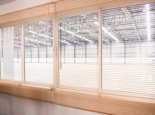 Fila de venecianas de aluminio en color madera bajadas sobre las ventanas corridas de una oficina en Burgos